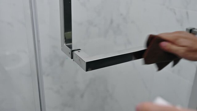 Hand cleaning with sanitizer and cloth wiping on handle rail of glass door