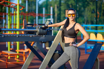 Naklejka na ściany i meble Beautiful fitness girl in glasses posing on an outdoor sports ground