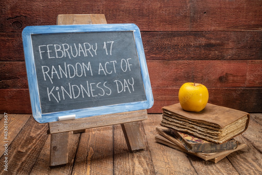 Wall mural random act of kindness day inspirational reminder  - white chalk handwriting on a vintage slate blackboard with old books against rustic wood background, social concept