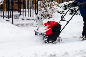 A man cleans snow from sidewalks with snowblower white blizzard