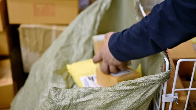 Delivery man scanning and put the parcel into sack from distribution center