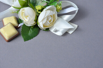 Decorative flowers and chocolate on a gray background.