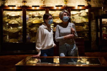 Attentive tween girl with senior woman exploring art museum