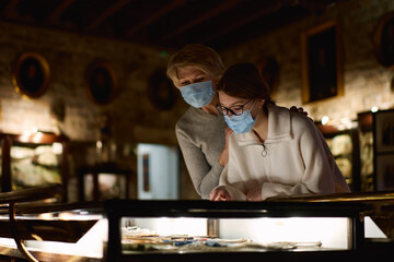 Attentive tween girl with senior woman looking with interest at gallery exposition
