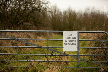 white sign with no parking in front of gates on a metal gate