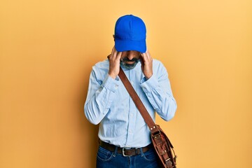 Middle age man with beard and grey hair wearing delivery courier cap with hand on head for pain in...