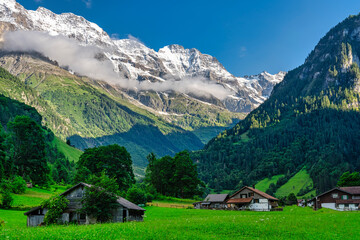 Fototapeta na wymiar village in the swiss alps on a summer day, with snowy mountains in the background - switzerland.