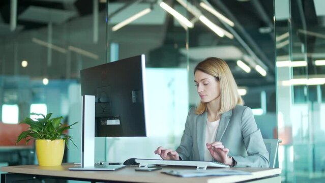 Female office worker in suit working at computer pc in front of monitor correspondence sitting at desk. employee in a modern workplace. Blonde woman Busy entrepreneur secretary typing text message