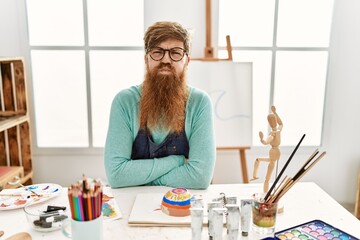 Redhead man with long beard painting clay bowl at art studio puffing cheeks with funny face. mouth inflated with air, crazy expression. - obrazy, fototapety, plakaty