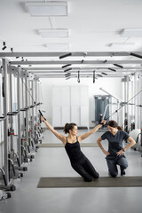 Fototapeta premium Young woman doing exercises on decompression simulators with the help of rehabilitation specialist. Concept of physical therapy for health and recovery. Idea of kinesiology in the treatment of back