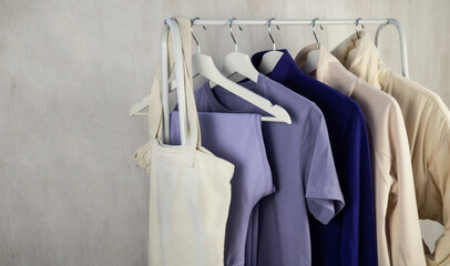 A white jacket, a lilac T-shirt and sweatpants, a sweatshirt are hanging on a hanger. Women's, youth clothes.