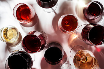 Red, white, rose wines in glasses in assortment on white background, top view. Wine bar, shop, winery, outdoor wine tasting concept. Hard light and harsh shadows
