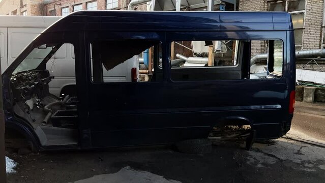 Broken and disassembled blue van abandoned on factory site