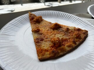 a piece of pizza with cheese on a disposable plate
