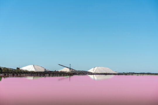 salt flats of Aigues Mortes with pink water and piles of salt behind.