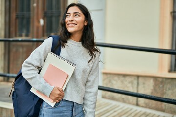 Young middle east student girl smiling happy holding book at the city.