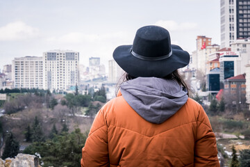 woman in black hat and red coat watching the city