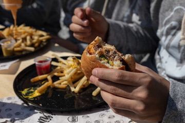 Man hands holding burger outdoors