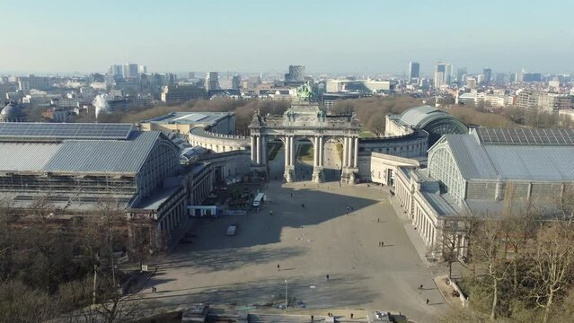 Drone aerial view at Cinquantenaire park (Jubelpark) and The Triumphal arch (Arc de Triomphe) with the European quarter and skyline of Brussels in the background