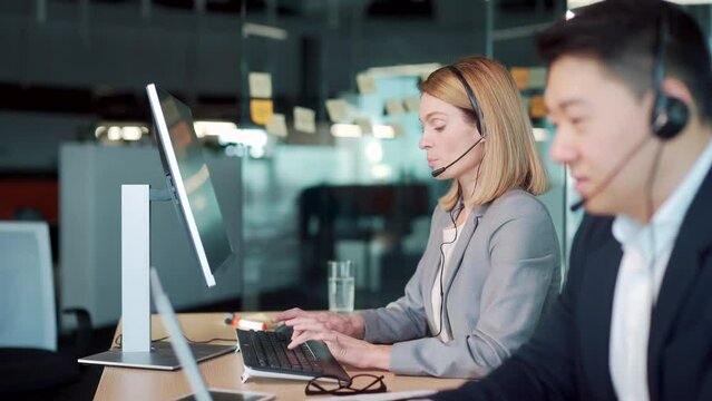 call center employee provide help to client distantly. Asian male customer services agent with headset working in online store helpline, smiling and talking to colleague Business people support remote