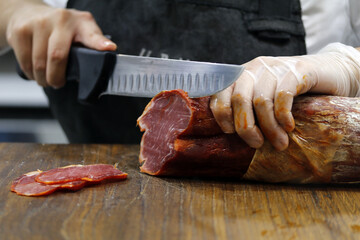 carnicero cortando lonchas lomo ibérico con cuchillo - obrazy, fototapety, plakaty