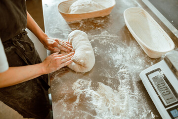 aker in apron kneads raw dough made of wheat flour in contemporary shop
