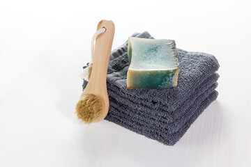 Spa set of grey towels, blue soap and wooden brush with natural bristles for the face on a white...