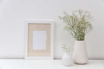 Blank canvas frame mockup. Artwork in interior design. View of modern scandinavian style interior with canvas for painting or poster on wall. Living room, commode with vases. Minimalism concept