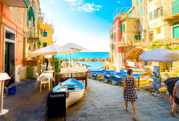 A woman walks down the boat launch at the colorful seaside village of Riomaggiore, Italy, one of...