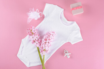 Baby girl shower mockup background, Flat lay composition layout with baby girl bodysuit, ceramic nipple or baby's dummy, gift box and confetti and hyacinth flowers with copy space on pink background