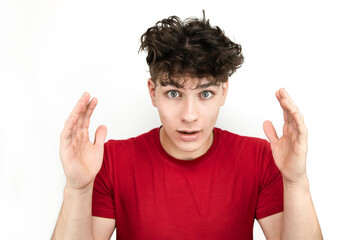 Teenager guy, young man with great surprise on his face, emotionally raised hands and uncombed hair on a light background, isolated. Glad guy with a surprise face