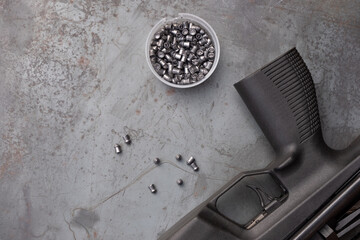 pneumatic shooting.an air rifle and bullets on a steel table. A black air rifle lies against the...