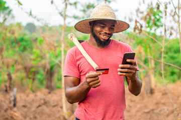 african farmer using his phone and bank card