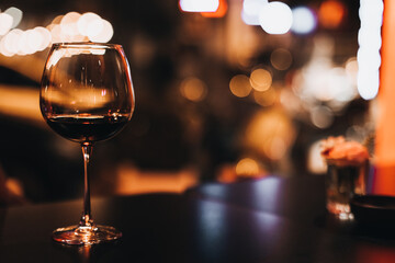 Red wine in a glass goblet against blurred evening lights