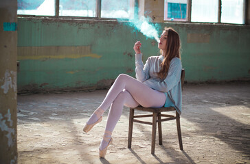 Ginger, blonde ballerina sitting on the chair smoking. Sport and smoking concept