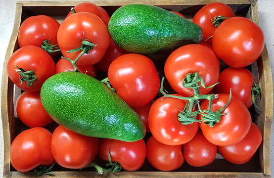 Red Tomato and green Avocado. Fresh vegetable in wooden box