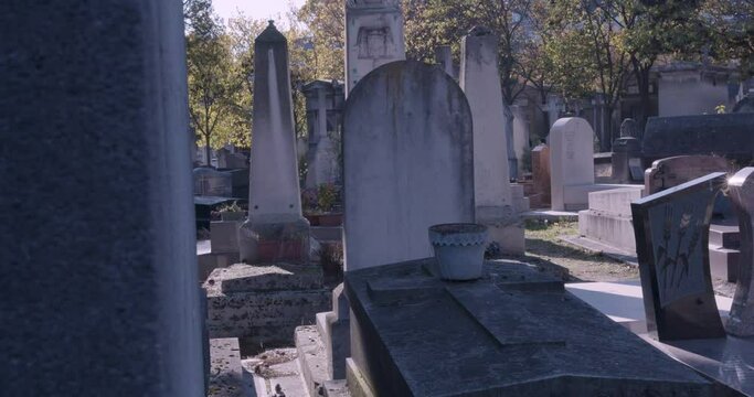 Pan shot left past large headstone in city cemetery lens flare