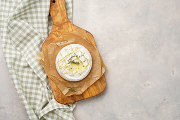 Oven baked camembert cheese with lye baguette bread on wooden board, grey concrete surface....