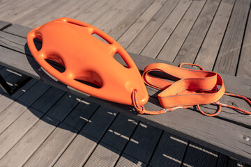 Podstawowe wyposażenie ratownika wodnego w kolorze pomarańczowym. Pomaga w utrzymaniu się na wodzie podczas udzielania pomocy. Ratownicy posiadają taki sprzęt zarówno na akwenach morskich jak i jezior - obrazy, fototapety, plakaty