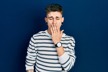 Fototapeta na wymiar Young caucasian boy with ears dilation wearing casual striped shirt bored yawning tired covering mouth with hand. restless and sleepiness.