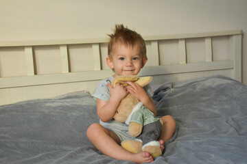 little boy on the bed with a soft toy 