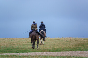 horse riding in open countryside under a blue grey cloud winter sky 