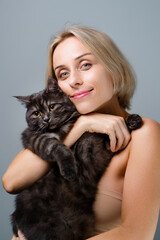 Studio portrait of young blode woman and her adorable black tabby cat.
