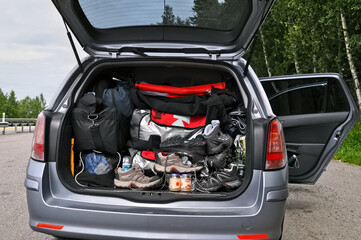 An open car trunk full of luggage loaded for a family vacation.