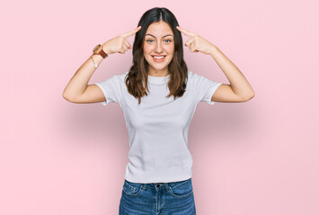 Young beautiful woman wearing casual white t shirt smiling pointing to head with both hands finger, great idea or thought, good memory