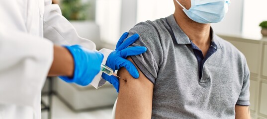 Young doctor woman injecting covid-19 coronavirus vaccine for man.