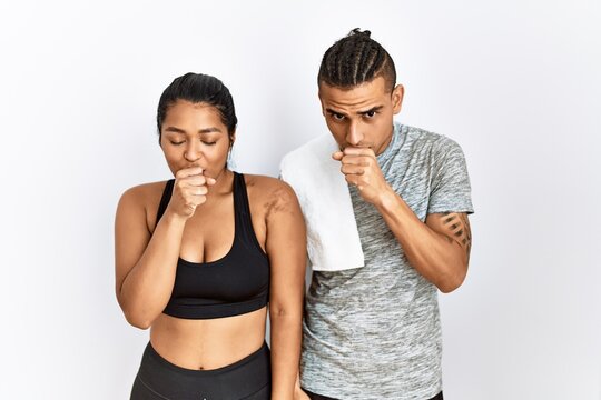Young latin couple wearing sportswear standing over isolated background feeling unwell and coughing as symptom for cold or bronchitis. health care concept.