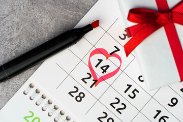 Close up calendar with 14 February date Valentines day with red heart shape marker and gift box