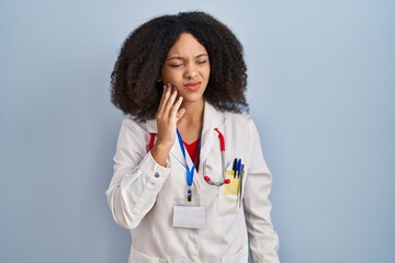 Young african american woman wearing doctor uniform and stethoscope touching mouth with hand with...
