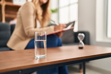 Young blonde woman psychologist writing on clipboard at psychology center
